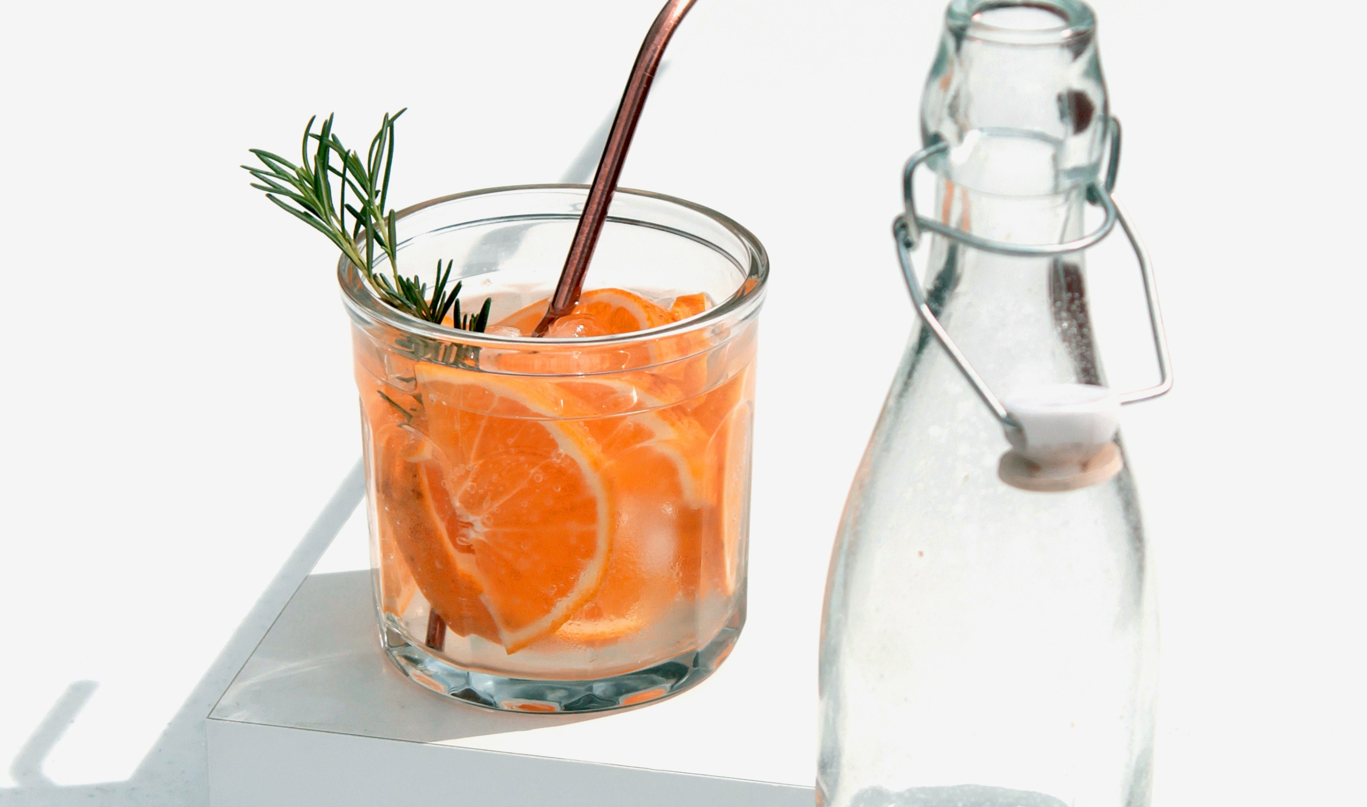 Orange drink in a glass beside a bottle