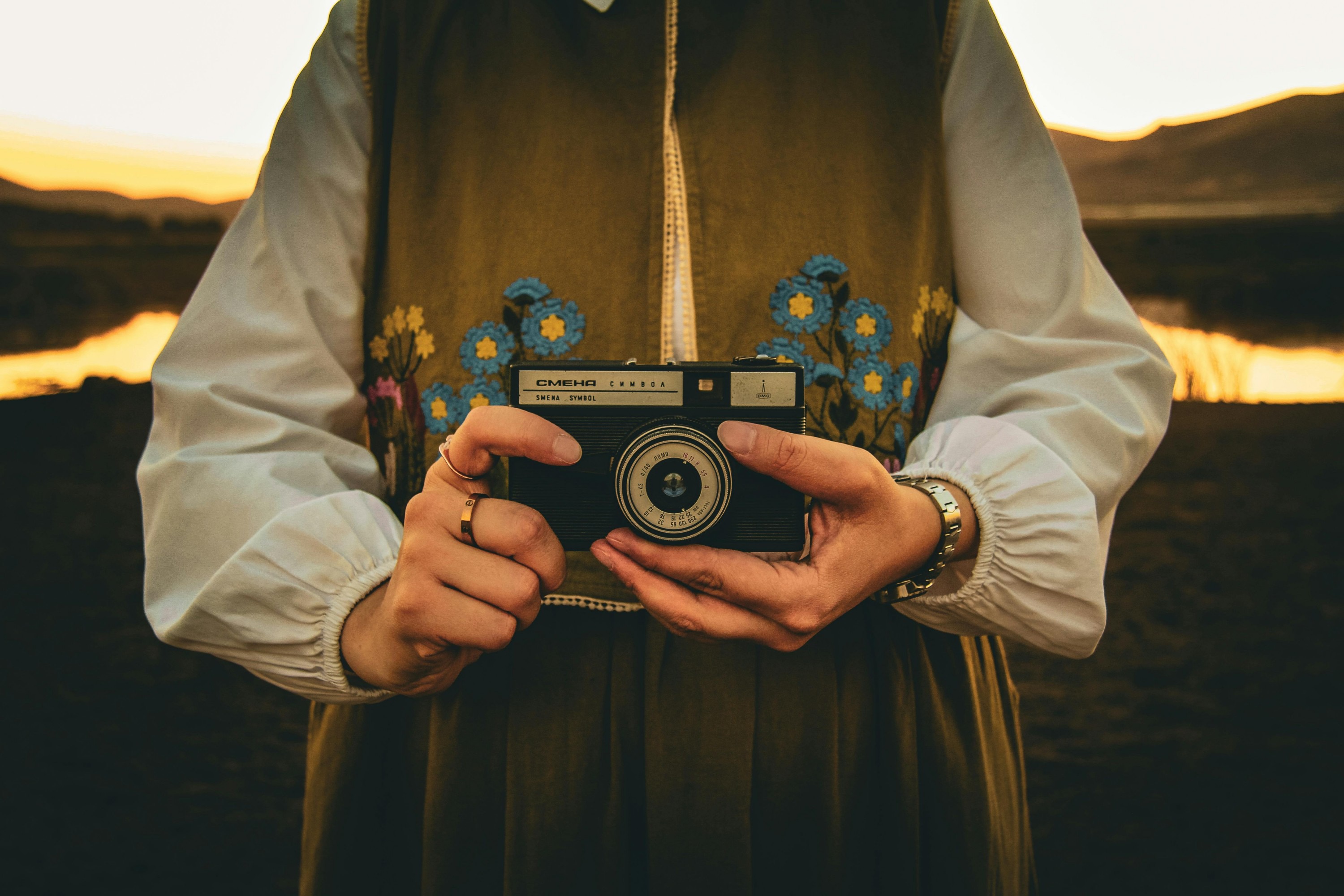 Hands holding a vintage camera at sunset